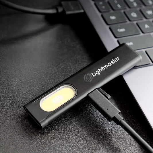 Lightmaster USB LED work light plugged into laptop on black textured surface